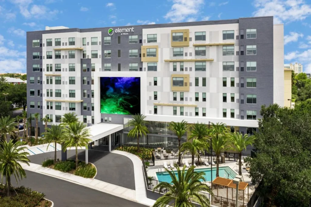 Element Orlando Universal Blvd. edificio con su dosel de entrada, palmeras y piscina al aire libre