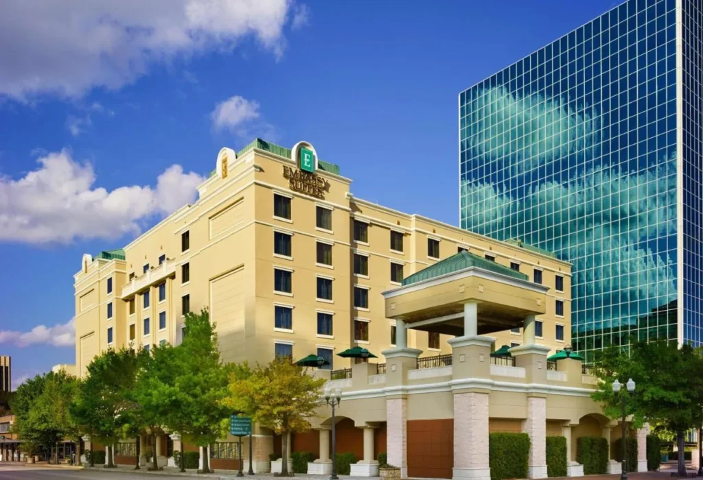 Embassy Suites by Hilton Orlando Downtown exterior con su entrada cubierta al lado de una torre de oficinas de vidrio