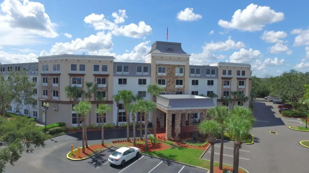 Entrance building with a stone-clad tower, porte-cochere and palms at Staybridge Suites Orlando Royale Parc Suites