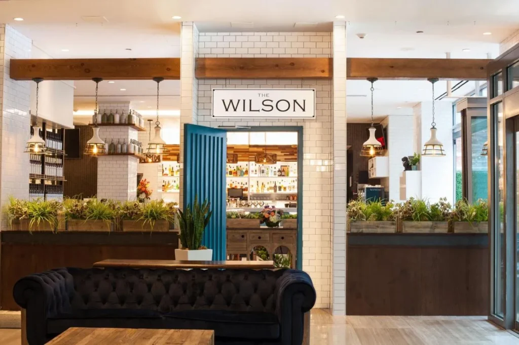 Entrada al restaurante The Wilson con puerta azul y jardineras en Meliá Orlando Celebration
