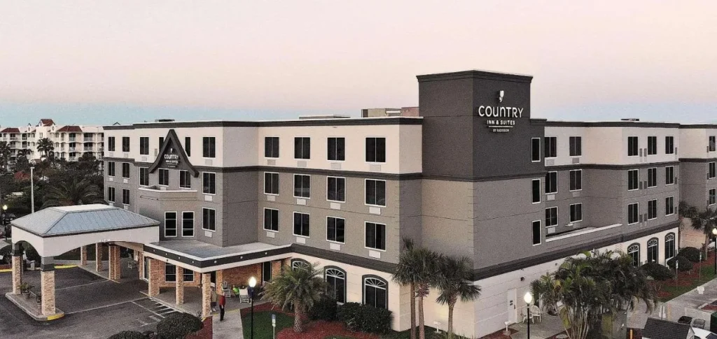Exterior and covered entrance of Country Inn & Suites by Radisson, Port Canaveral, at dusk