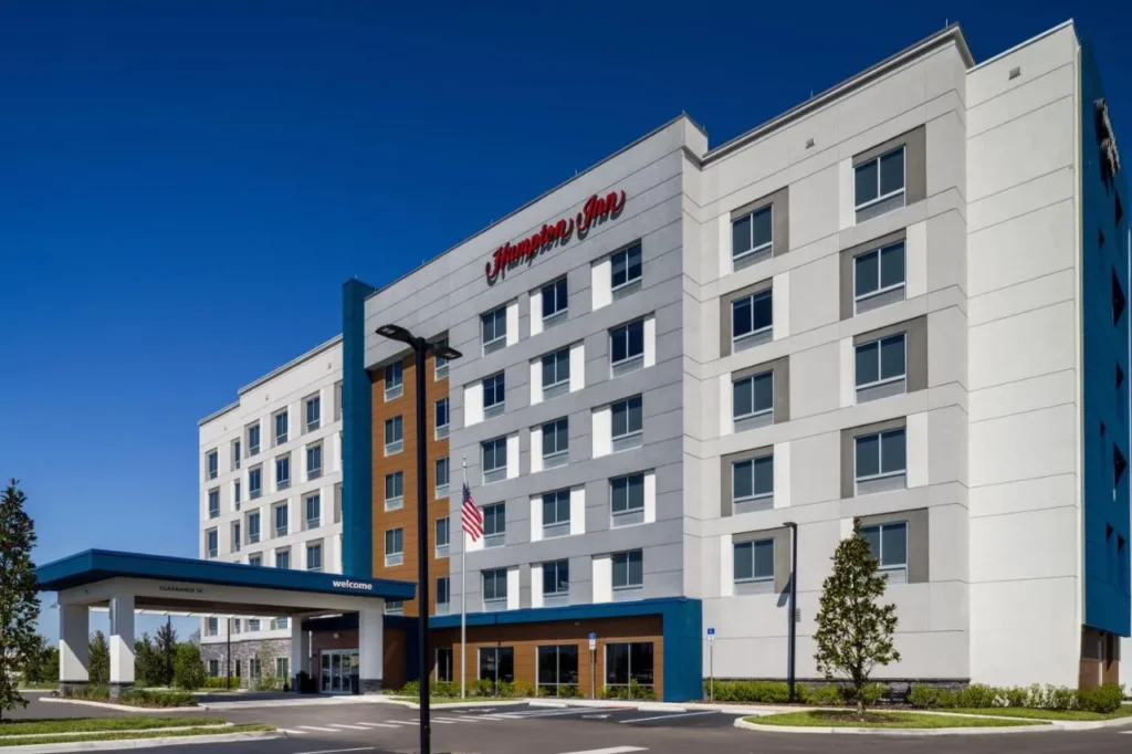 Exterior y entrada cubierta de Hampton Inn Kissimmee North bajo un cielo azul claro
