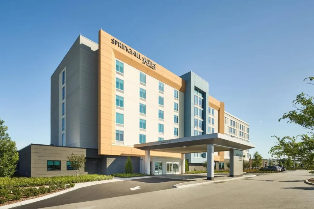 Exterior y dosel de entrada de SpringHill Suites by Marriott Orlando Lake Nona bajo un cielo azul