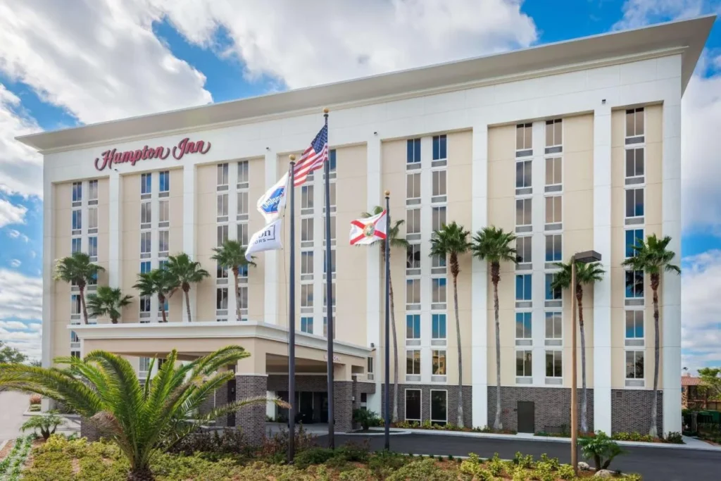 Exterior of Hampton Inn Orlando Near Universal Blv/International Dr with flags and palm trees