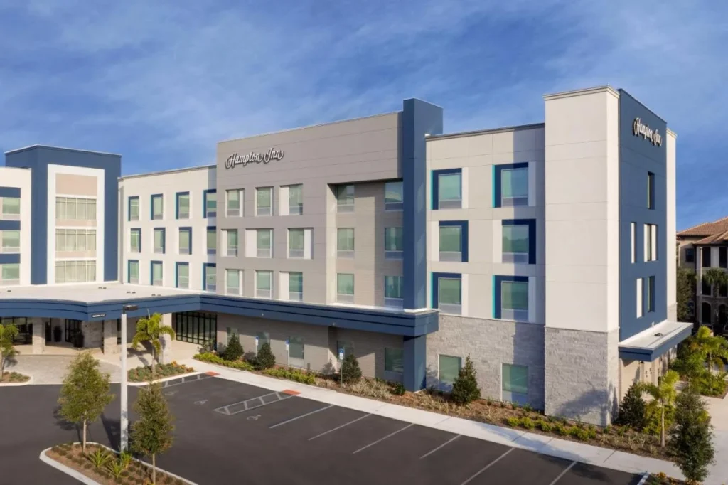 Exterior of Hampton Inn Orlando Southeast Nona with blue and gray facade and parking lot