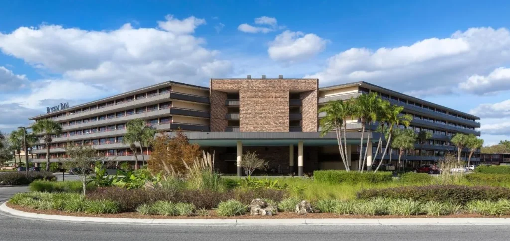Exterior of Rosen Inn International with its entrance canopy, palm trees and landscaped drive