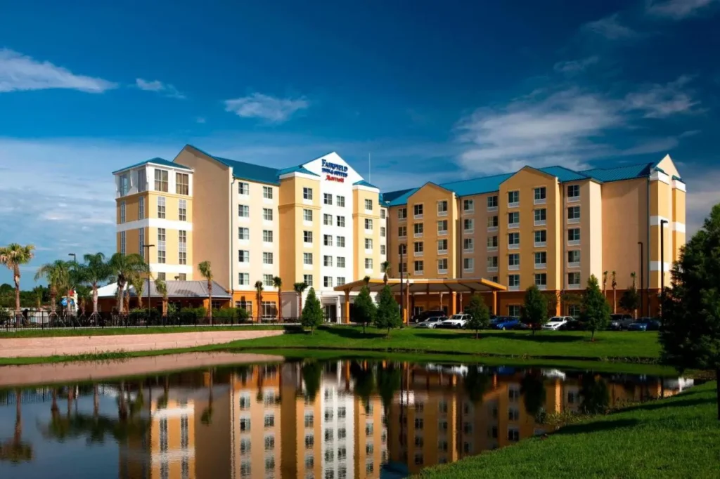 Fairfield Inn & Suites Orlando at SeaWorld se refleja en un estanque bajo un cielo azul
