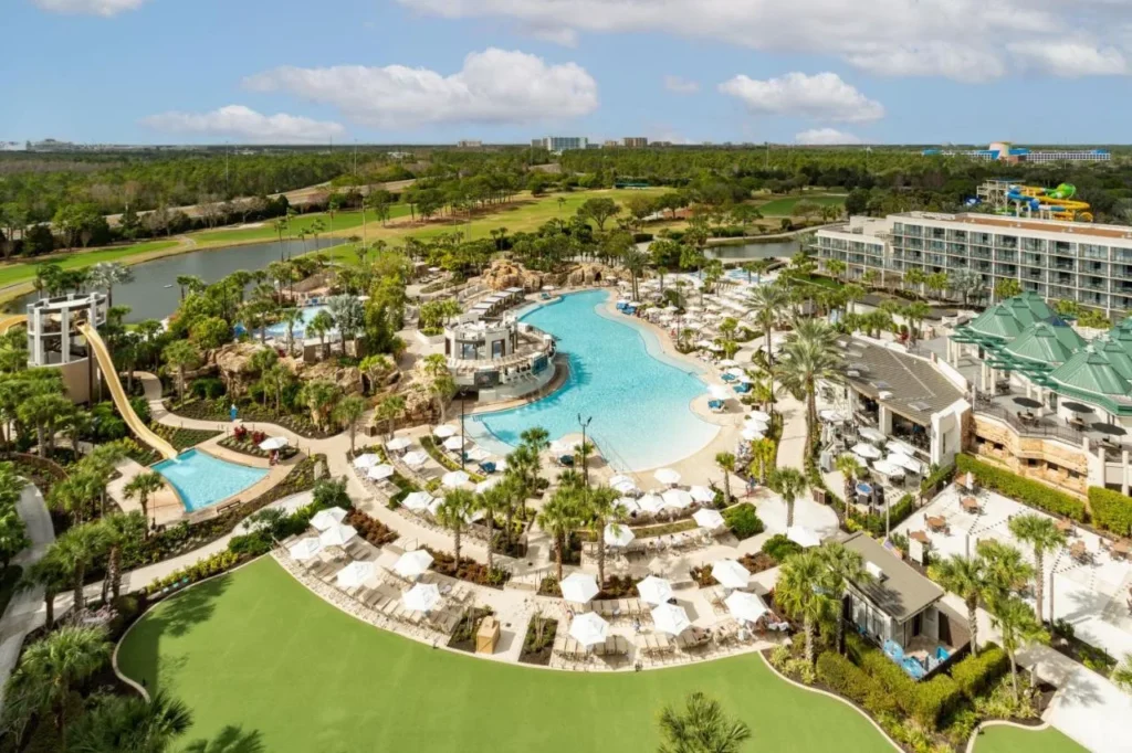 Falls Pool Piscina tipo laguna Oasis con sombrillas, palmeras y torre corrediza en el Orlando World Center Marriott