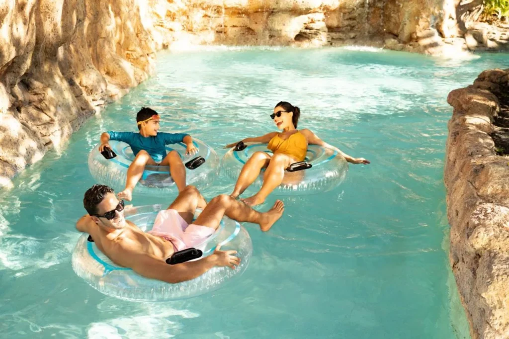 Familia flotando en tubos a lo largo del río flojo bordeado de rocas en Grande Lakes, compartido por el Ritz-Carlton Orlando