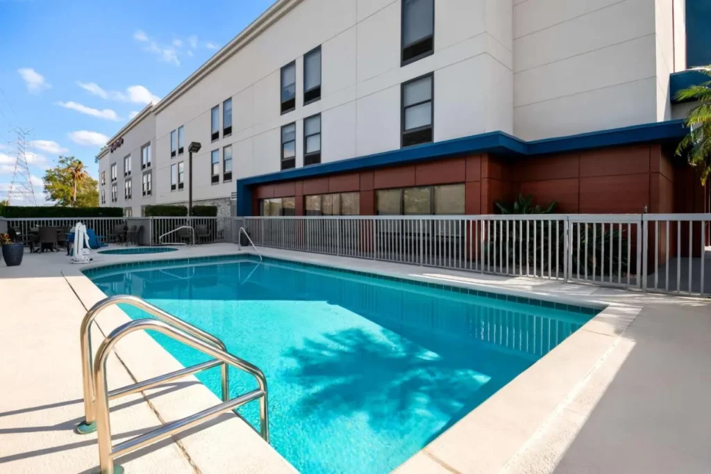 Fenced outdoor pool and small spa beside the white Hampton Inn Debary-Deltona building