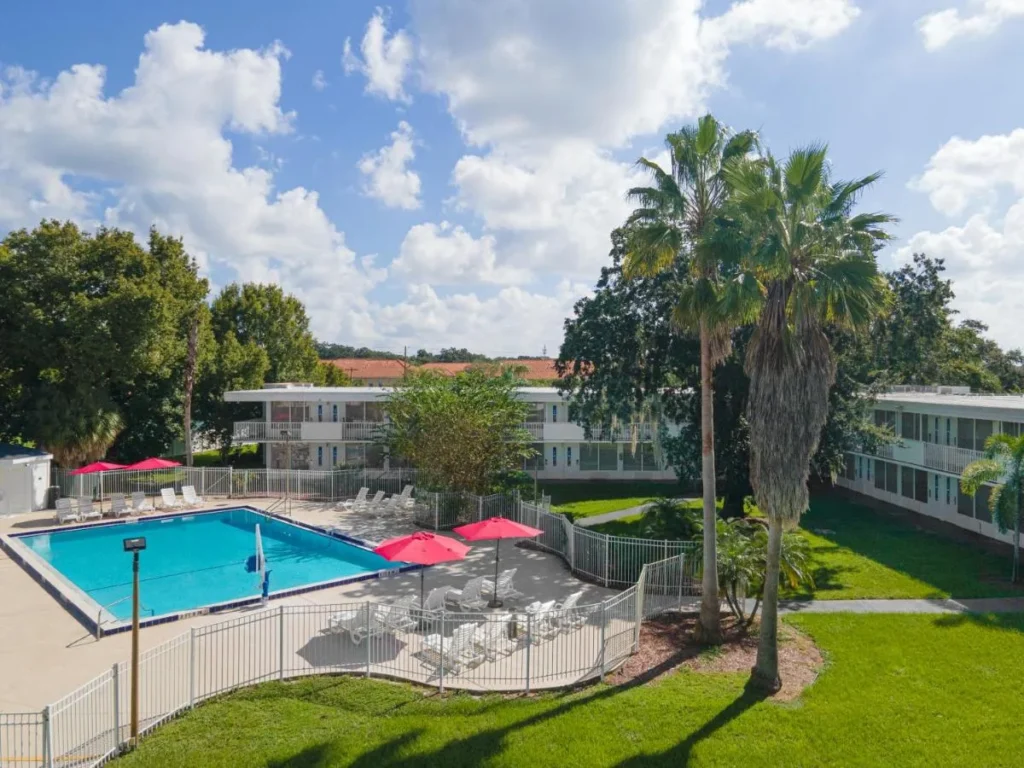 Fenced outdoor pool with red umbrellas at Baymont by Wyndham Lake Buena Vista South