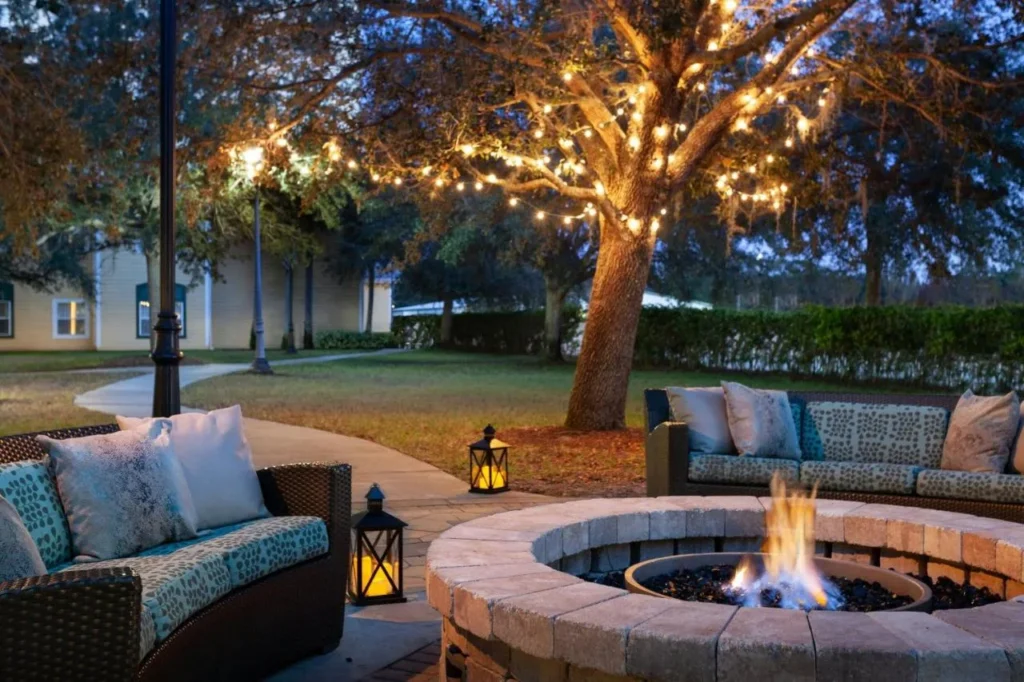 Fogata y sofás de mimbre bajo guirnaldas de luces en Residence Inn Orlando at SeaWorld