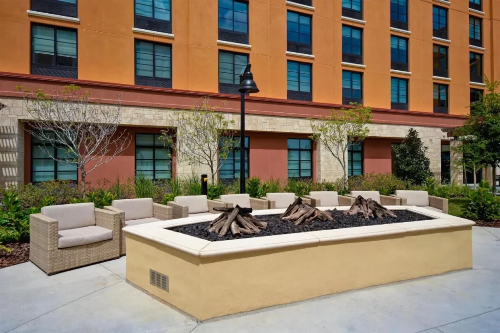 Fire pit lounge with wicker armchairs in front of Homewood Suites by Hilton Flamingo Crossings