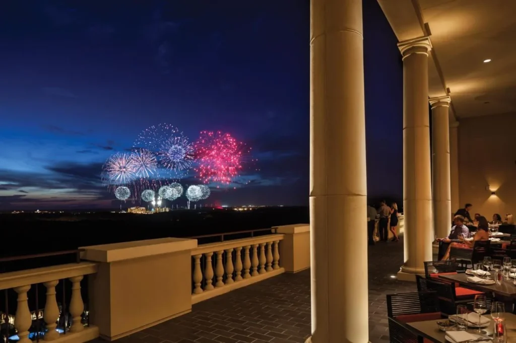 Fireworks seen at night from a columned dining terrace at Four Seasons Resort Orlando