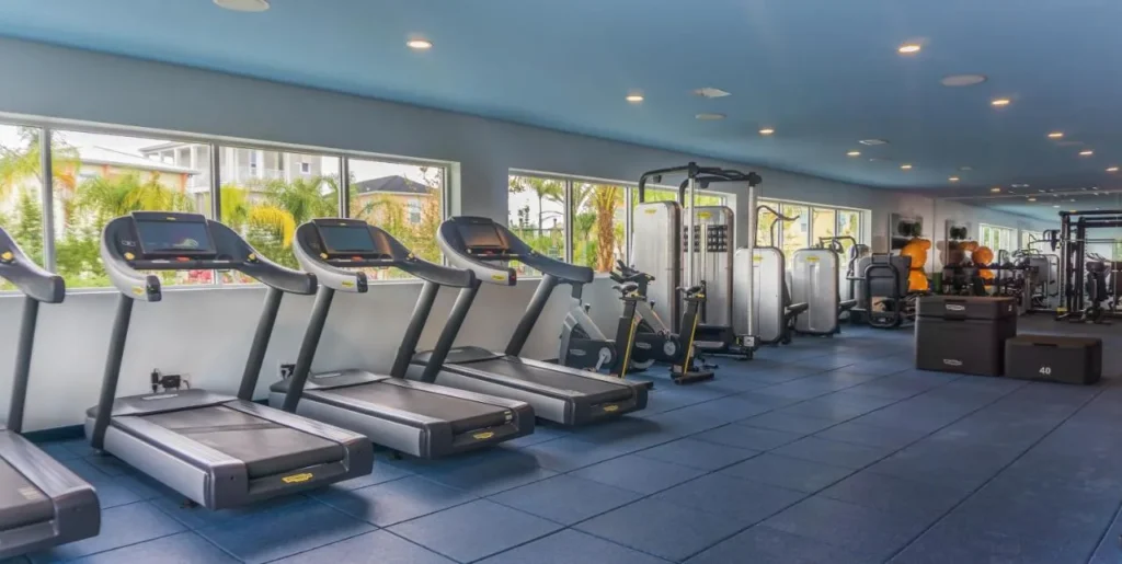 Fitness center at Margaritaville Resort Orlando with treadmills, weight machines and windows onto palm trees
