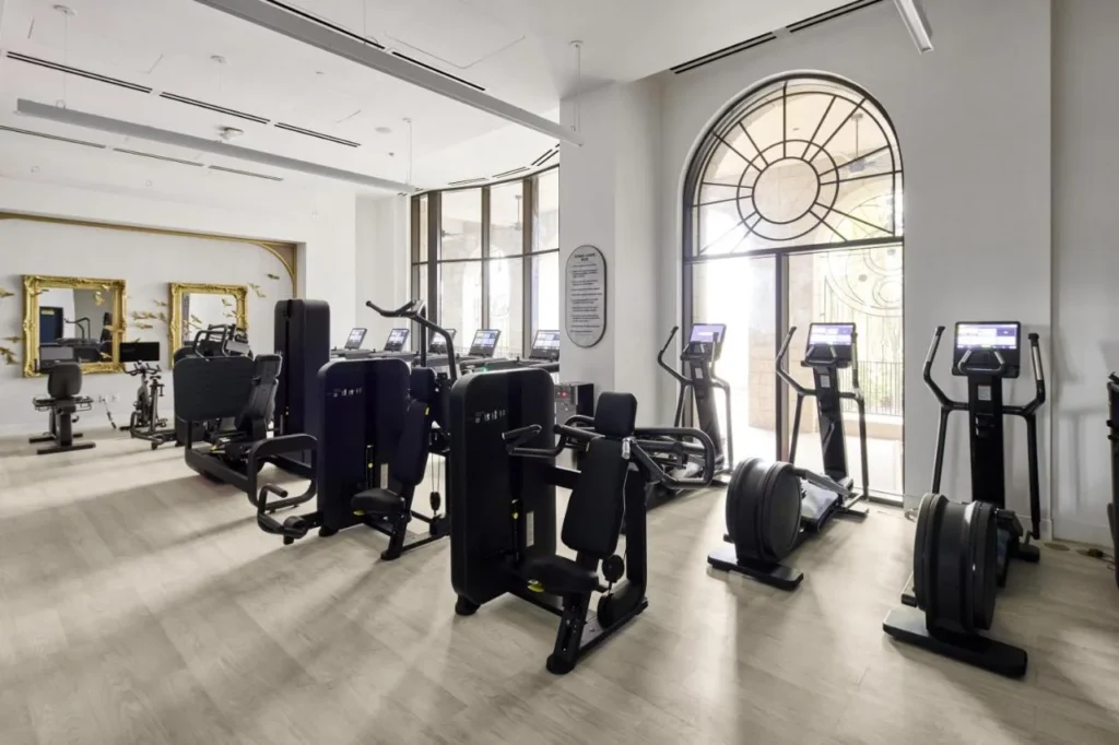 Fitness center with cardio machines, strength equipment and an arched window at Universal Helios Grand Hotel