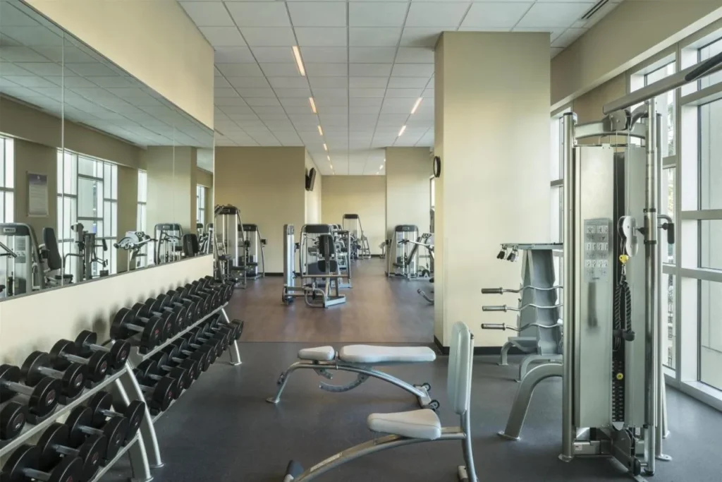 Gimnasio con estantes con mancuernas, m&aacute;quinas de pesas y ventanas altas en Hyatt Regency Orlando