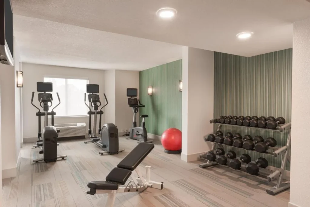 Fitness center with ellipticals, exercise bike, weight bench and dumbbells at Holiday Inn Express Nearest Universal