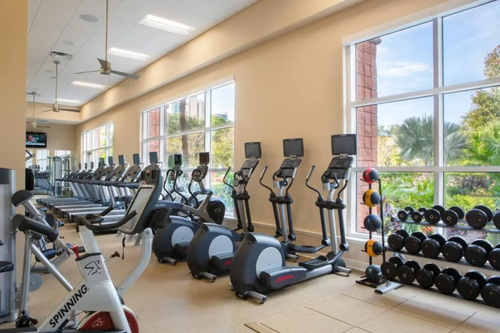Gimnasio con elípticas, cintas de correr, mancuernas y ventanas con vistas al jardín en el Rosen Centre Hotel