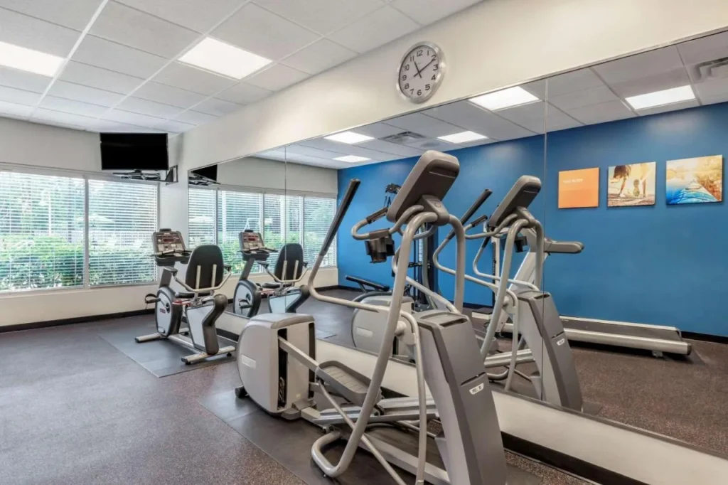 Gimnasio con bicicleta reclinada, el&iacute;ptica, cinta de correr y pared de espejo en Comfort Suites Maingate East