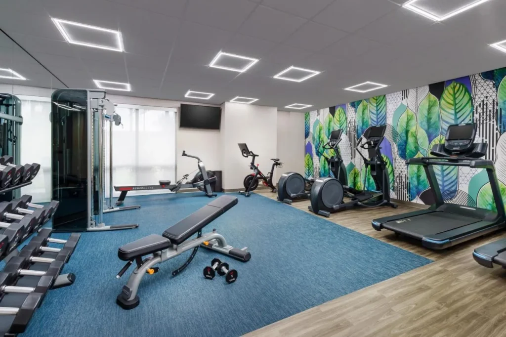 Gimnasio con cinta de correr, elípticas, banco de pesas y mancuernas en Hyatt Place across from Universal