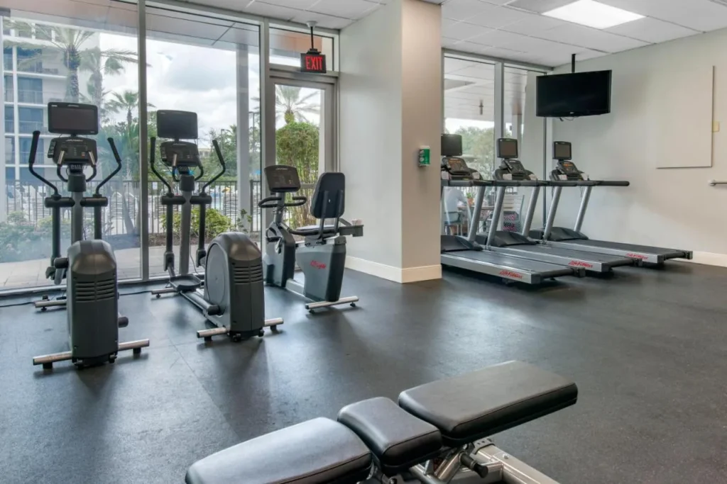 Gimnasio con cintas de correr y elípticas frente a la piscina, Holiday Inn Orlando Disney Springs