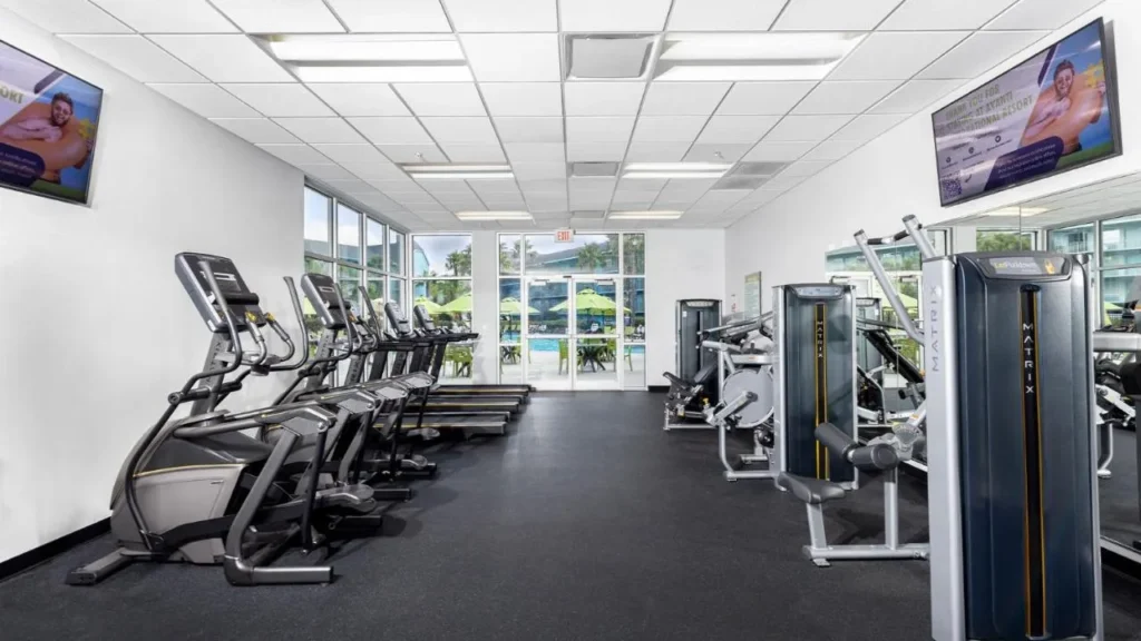 Gimnasio con cintas de correr, el&iacute;pticas y m&aacute;quinas de pesas frente a la piscina en Avanti International Resort