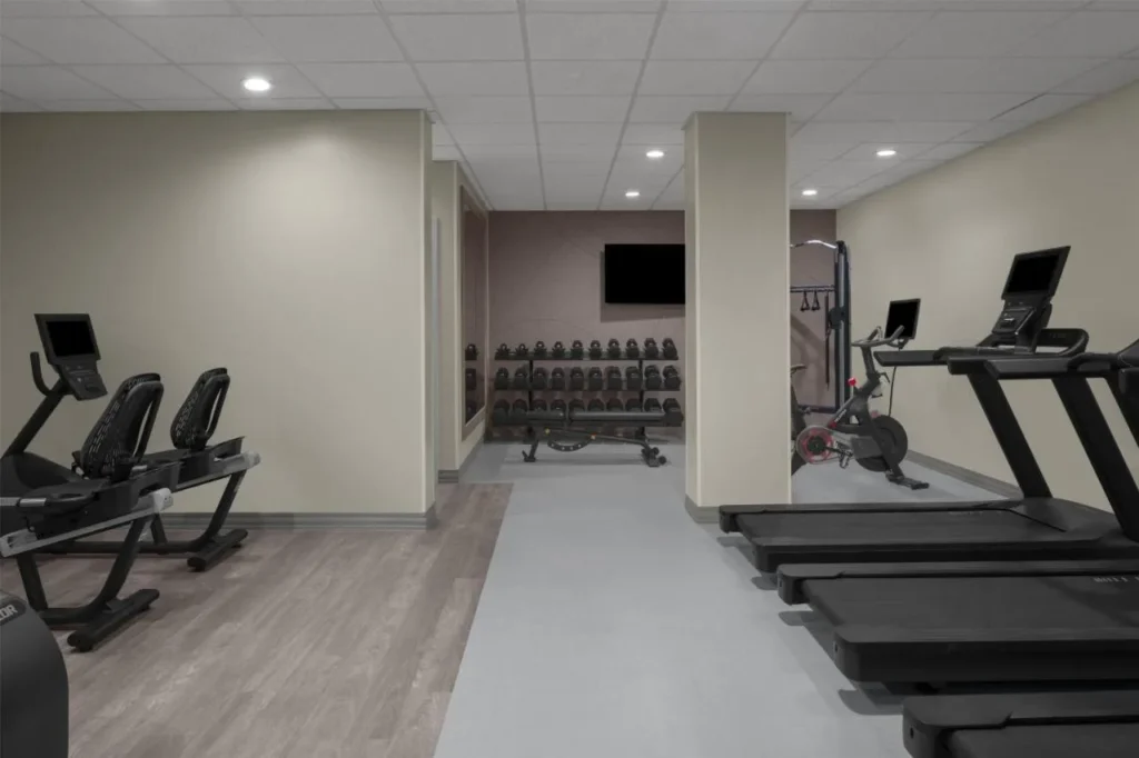Gimnasio con cintas de correr, bicicletas est&aacute;ticas y soporte para mancuernas en Embassy Suites Orlando ICON Park