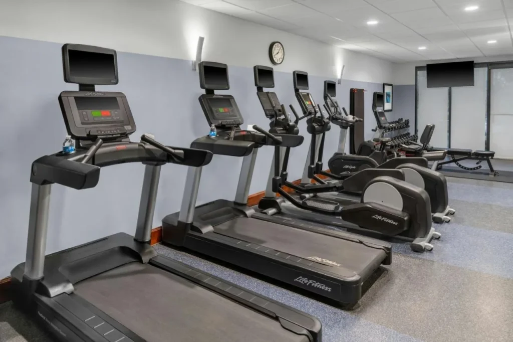 Sala de fitness con cintas de correr, máquinas elípticas y un banco de pesas en Four Points Orlando International Drive