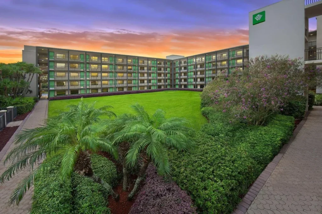 Edificio de Courtyard de cinco pisos, césped y palmeras al atardecer en Wyndham Garden Lake Buena Vista