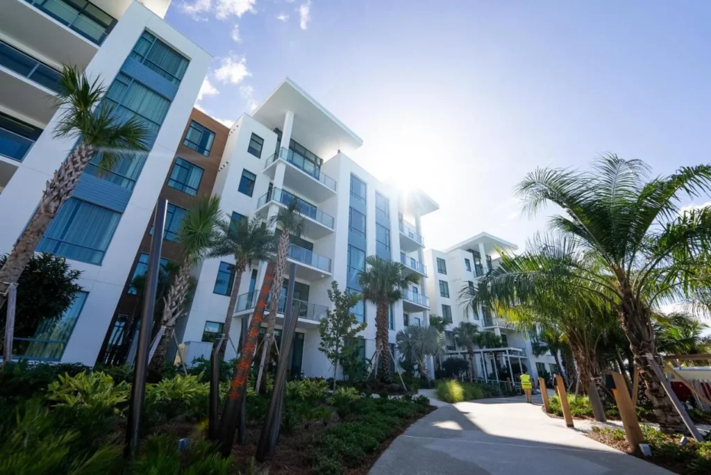 Five-story Tower Flats buildings with balconies along a palm-lined path at Evermore Orlando Resort