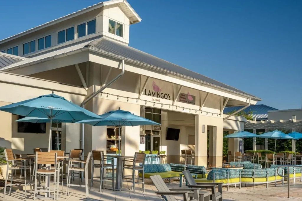 Flamingo's Bar & Grille patio con sombrillas azules y mesas altas en el SpringHill Suites Flamingo Crossings