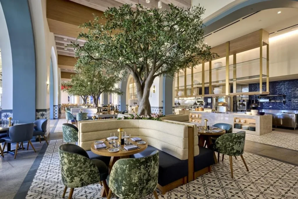 Flora Taverna restaurant at Universal Helios Grand Hotel with olive trees, booths and an open kitchen