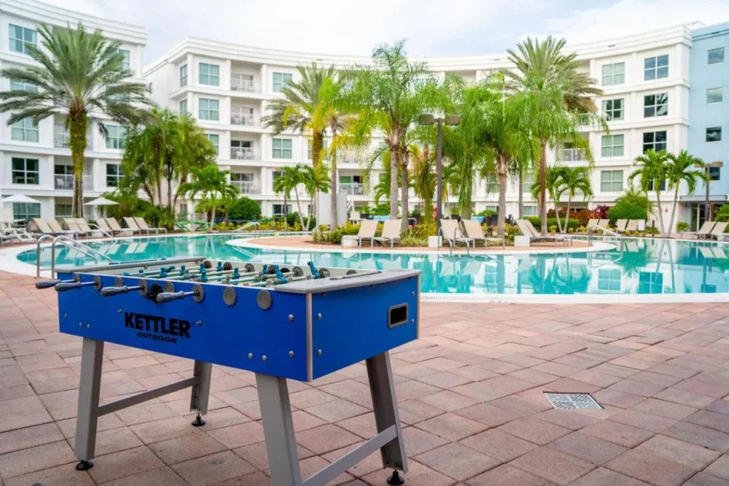 Mesa de futbolín en la terraza de la piscina con palmeras y edificios para invitados en Meliá Orlando Celebration