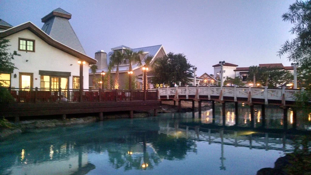 Footbridge and lit shops reflected in the waterway at Disney Springs Town Center at dusk