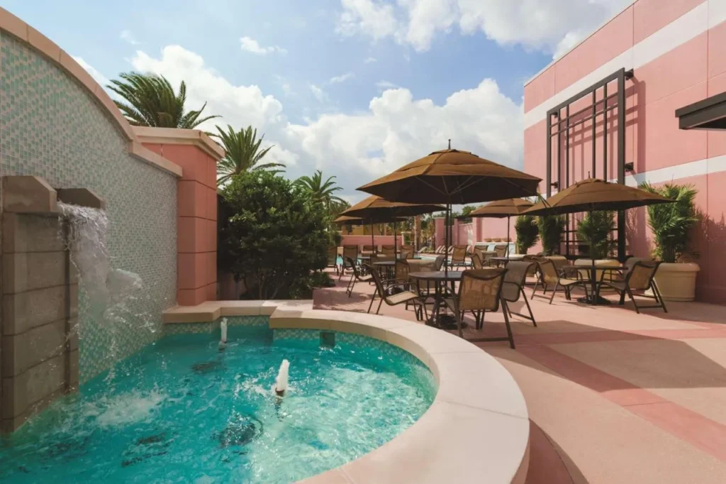 Fuente y patio con mesas de sombrilla en Embassy Suites Lake Buena Vista South
