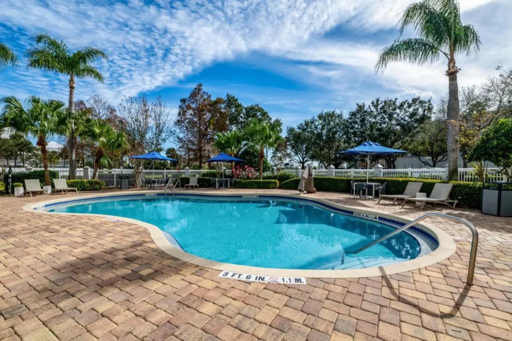 Free-form outdoor pool with brick deck, palms and umbrellas at Hampton Inn Orlando/Lake Buena Vista