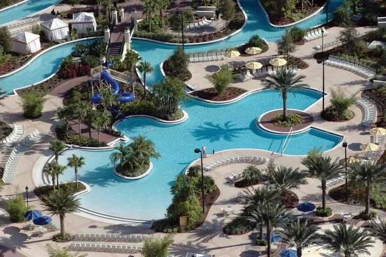 Free-form pool with a blue twisting waterslide, cabanas and palm islands at Orange Lake Resort