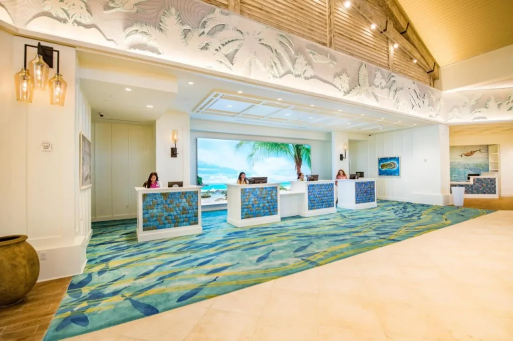Front desk at Margaritaville Resort Orlando with mosaic counters, fish-pattern carpet and a beach video wall