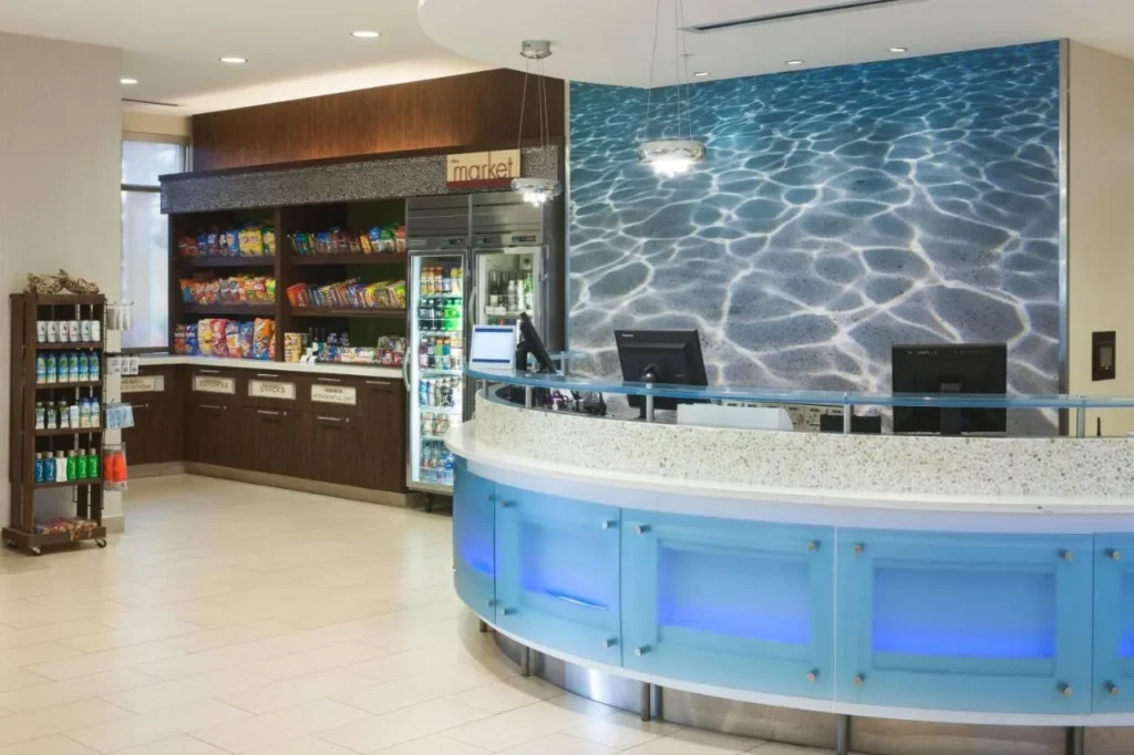 Front desk with a blue-lit counter and the grab-and-go market at SpringHill Suites Orlando at SeaWorld