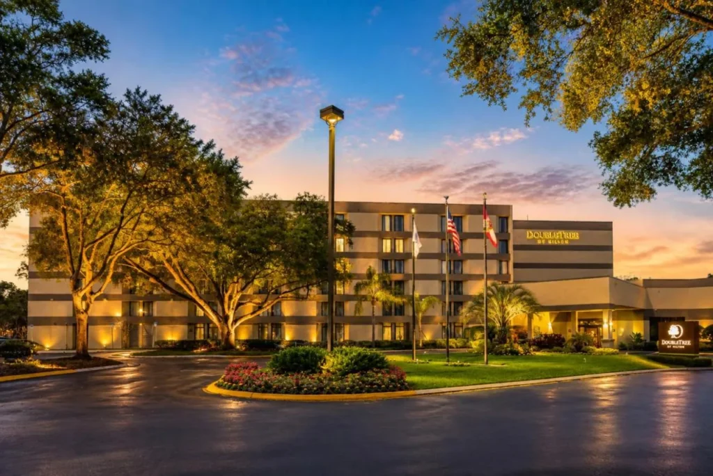 Conducción delantera, banderas y robles al atardecer en DoubleTree by Hilton Orlando East-UCF Área