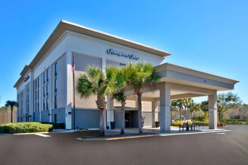 Entrada frontal y porte-cochere con palmeras en Hampton Inn Daytona / Ormond Beach