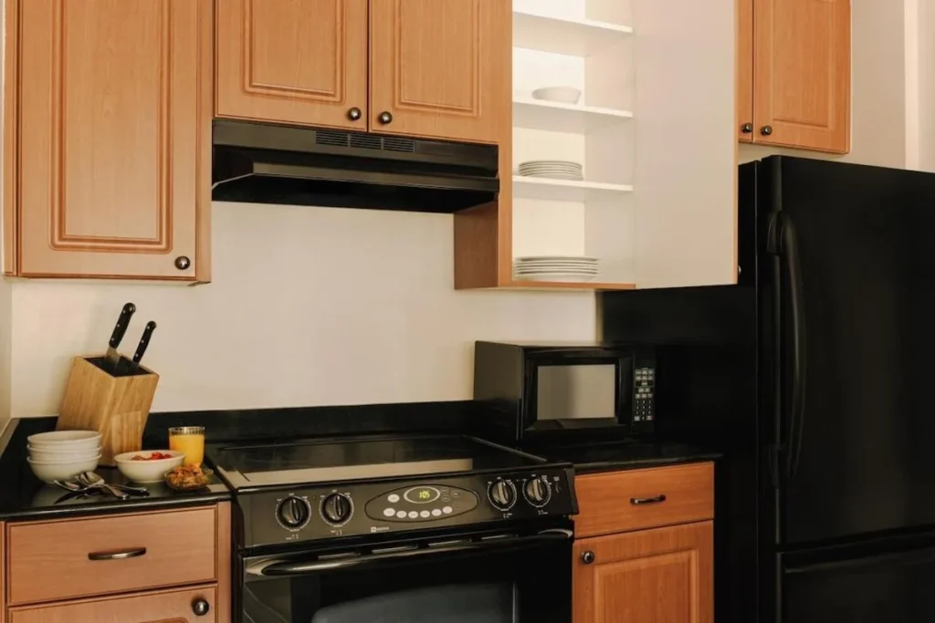 Full suite kitchen with electric stove, microwave and black refrigerator at The Point Hotel & Suites