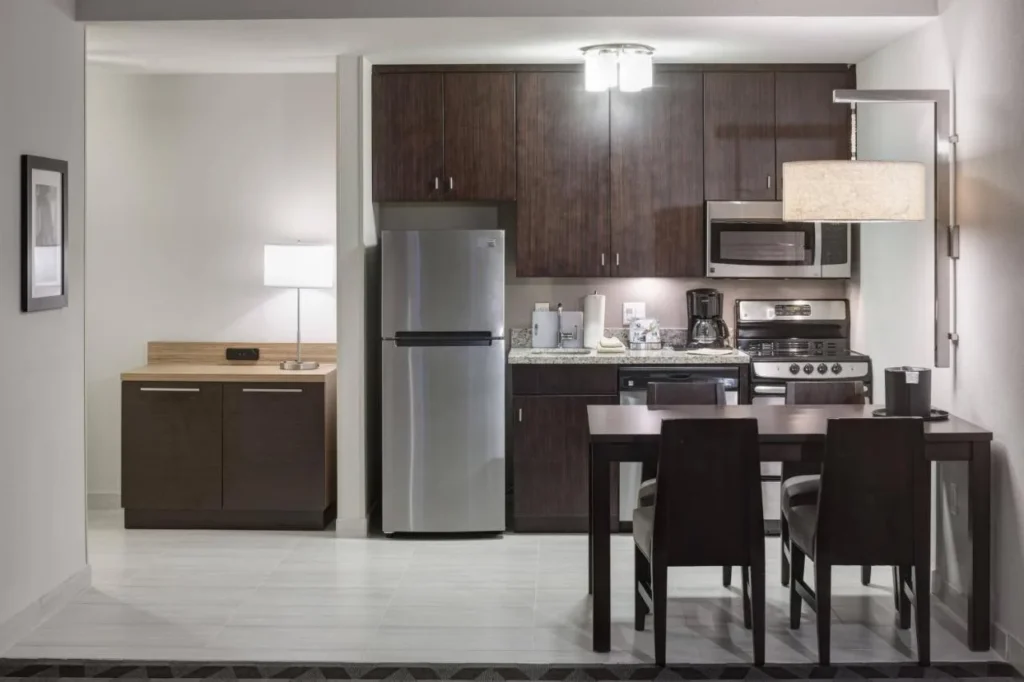 Cocina de suite completa con refrigerador, estufa y mesa de comedor en TownePlace Suites Orlando at SeaWorld