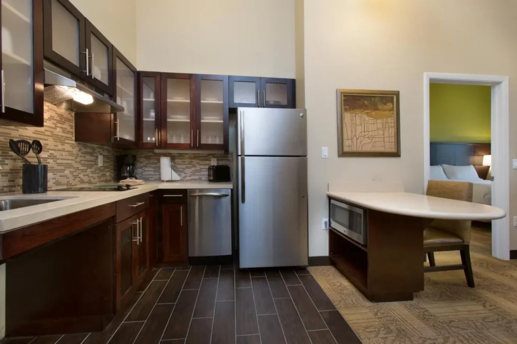 Cocina de suite completa con refrigerador de acero inoxidable y mostrador de comedor en Staybridge Suites Orlando at SeaWorld