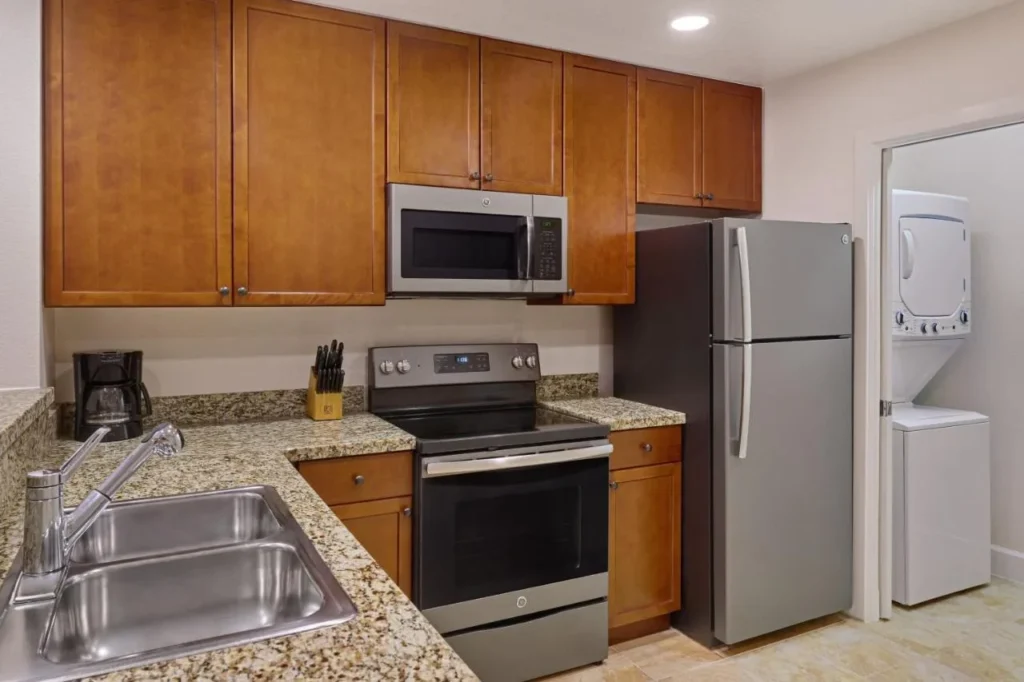 Cocina completa con horno, microondas y refrigerador junto a una lavadora-secadora apilada en Sheraton Vistana Villages