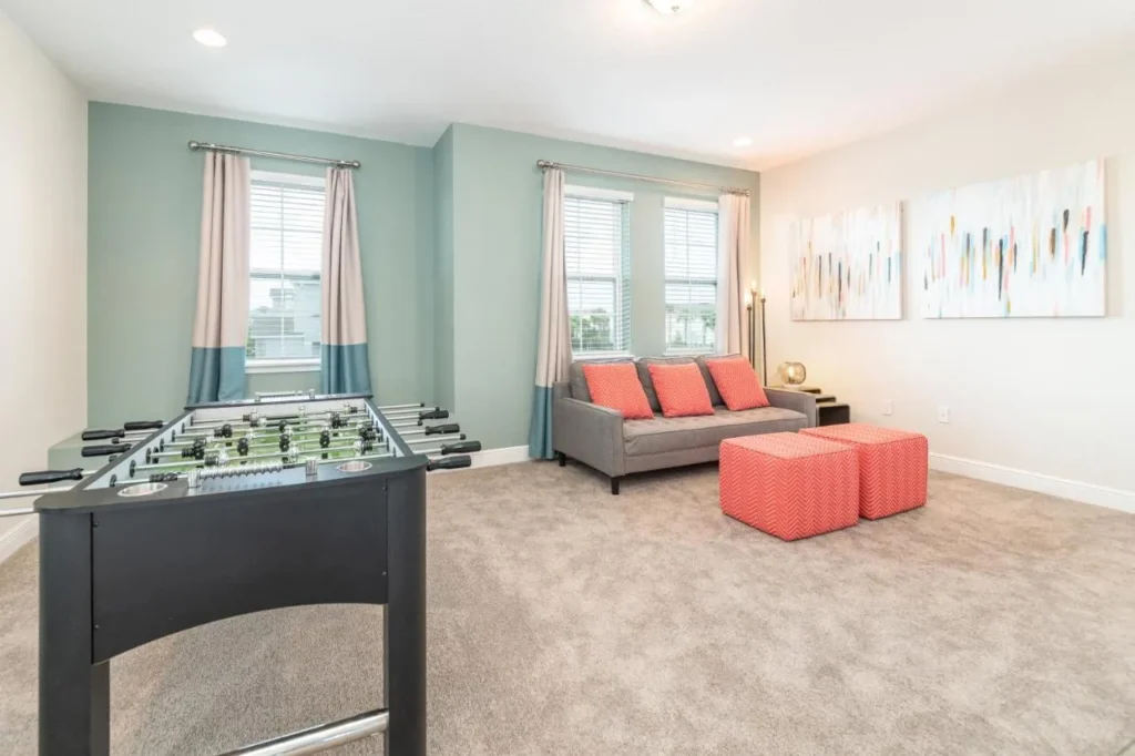 Game room with a foosball table, gray sofa and coral ottomans in an Encore Resort home
