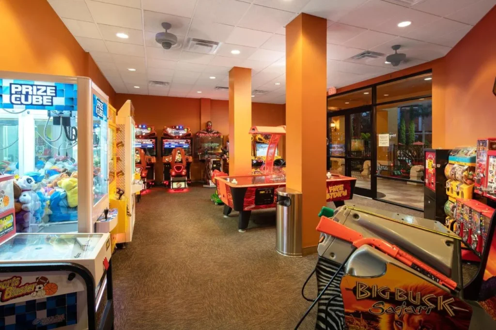 Sala de juegos con m&aacute;quinas recreativas, juegos de garras y una mesa de air hockey en Floridays Resort Orlando