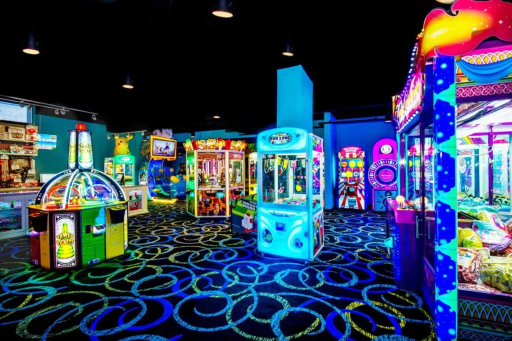 Sala de juegos con máquinas recreativas de neón y juegos de garras en The Grove Resort Orlando