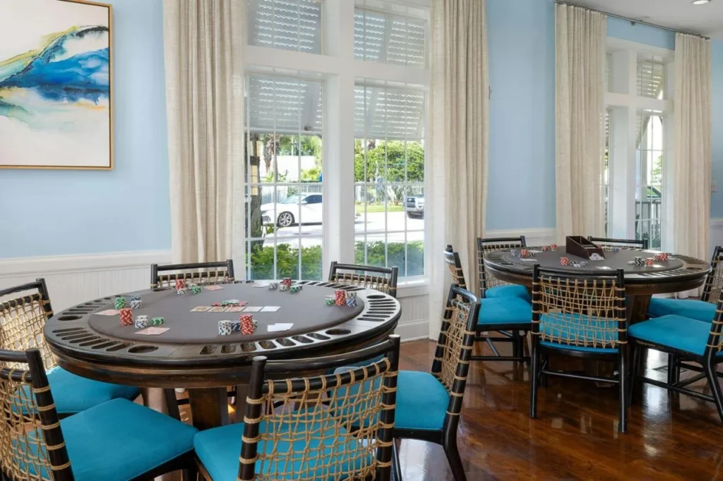 Sala de juegos con dos mesas de cartas y sillas con acolchado azul en Marriott's Harbour Lake
